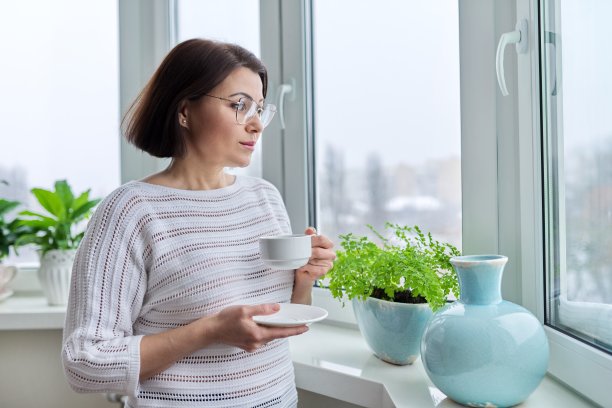 中年美女用玻璃杯和一杯咖啡在冬天的秋天图片下载