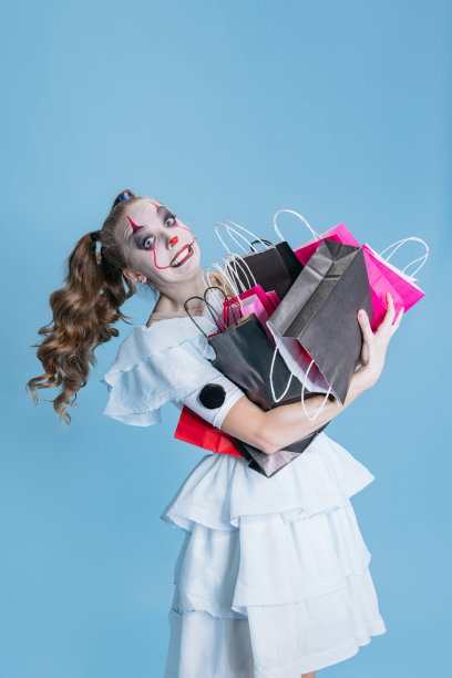 年轻女孩的形象跳舞小丑与明亮的化妆去购物。庆祝万圣节和黑色星期五图片下载