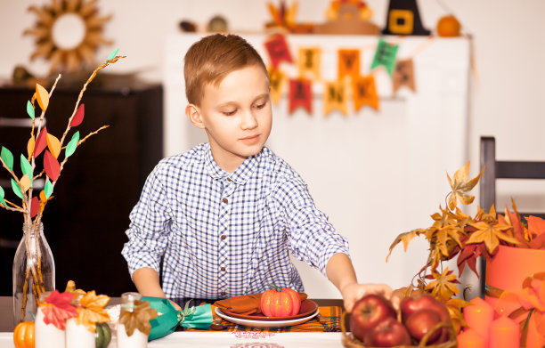为庆祝感恩节，男孩端上餐桌，装饰客厅。图片下载