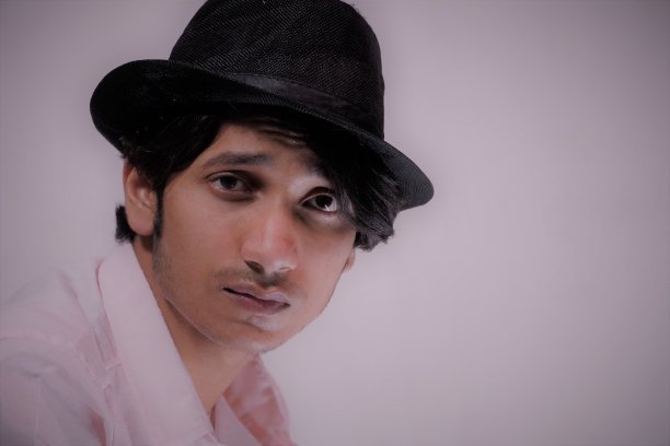 近距离的肖像微笑英俊的男子，穿着粉红色的衬衫和黑色的帽子。图片下载