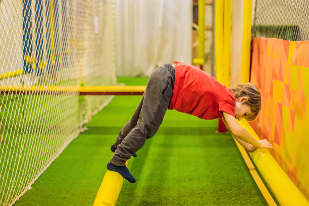 6岁男孩的肖像，戴着头盔，正在攀登。儿童在冒险游乐场的障碍课程图片下载