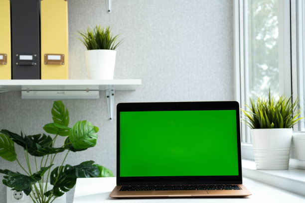 摩登笔记本绿色屏幕。色度键绿色屏幕电脑设置工作桌上在家里或办公室，技术概念。空笔记本广告图片下载