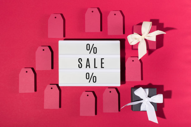 销售文字在白色灯箱，黑色和红色的礼品盒，白色雪花在红色的纸背景。图片下载