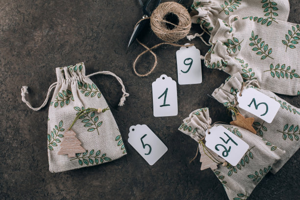 准备圣诞节来临日历。包裹在织物环保袋的礼物。平铺，俯视图。图片下载