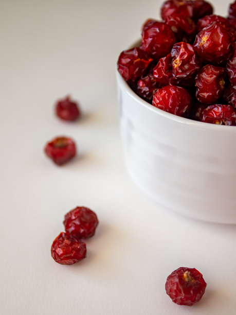 晒干的野玫瑰果放在白碗里图片下载