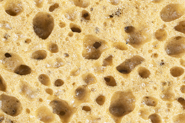 微距拍摄的表面塑料黄色海绵的背景。特写纹理。黄色擦洗海绵图案。海绵质地的背景。黄色海绵背景图片下载