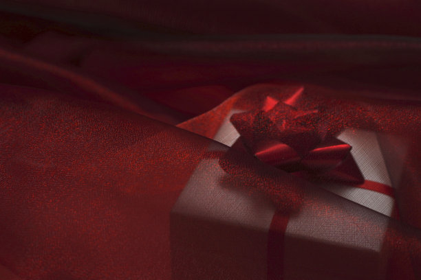 礼品盒下透明的红色真丝织物。圣诞节，新年，生日，情人节，妇女节，购物销售理念。图片下载