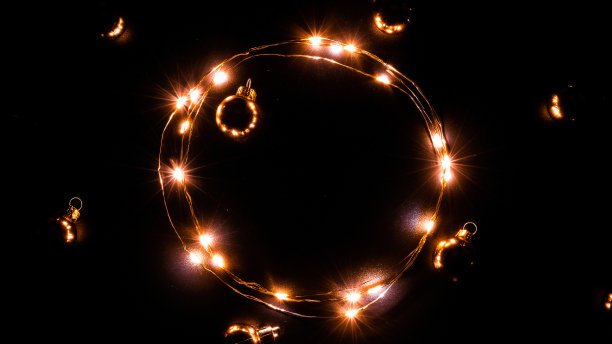 圣诞灯。金光花环装饰，金色灯泡孤立在黑色为圣诞派对装饰背景。圣诞节的灯火辉煌。图片下载