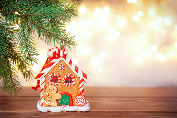 圣诞姜饼屋在木桌上，杉枝在散景灯的背景上。副本的空间。贺卡，新年快乐，圣诞快乐。图片下载