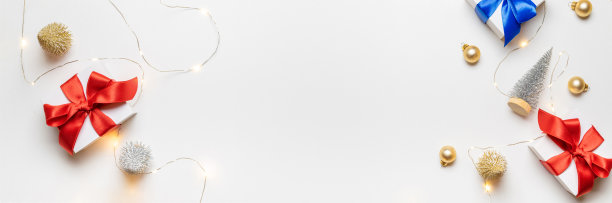 圣诞礼物。白色的礼物与红色的蝴蝶结，金球和闪闪发光的灯在圣诞节装饰在白色的背景贺卡。圣诞节背景与空间的文本。图片下载