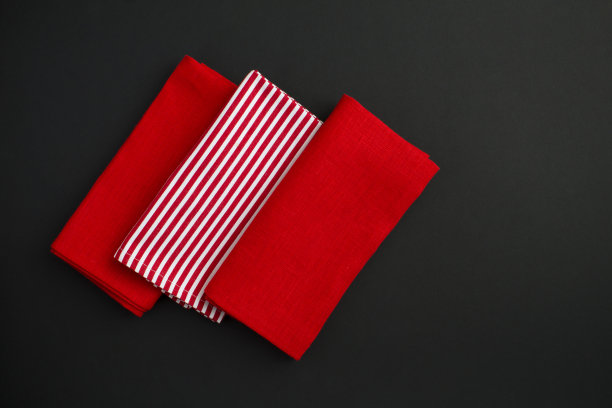红色和条纹餐巾在黑色背景上的俯视图。副本的空间。特写镜头。图片下载