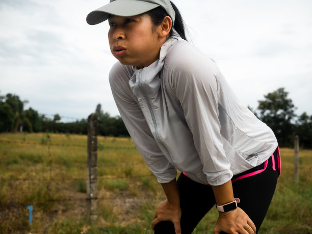 疲累的女跑步者在晨跑后正在进行健身训练。健康的生活方式的概念。运动员在户外跑步锻炼。图片下载