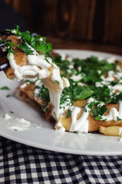 餐厅里盘子里有奶酪的薄饼。在咖啡馆吃早餐。一位妇女用一次性盘子吃煎饼当早餐。俯视图和垂直照片图片下载