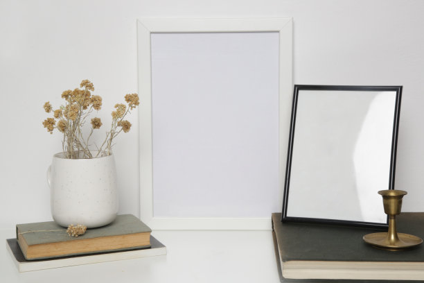 木制框架模型桌上与家庭室内装饰元素。书，陶瓷杯和干花中性调色板。白墙的背景。图片下载