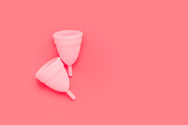 粉红色月经杯上的颜色背景，女性亲密卫生的时期产品，顶部视图图片下载
