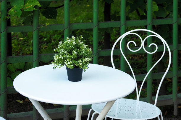 绿色公园里的古董家具和桌子。桌上摆着鲜花的花瓶。空桌椅图片下载