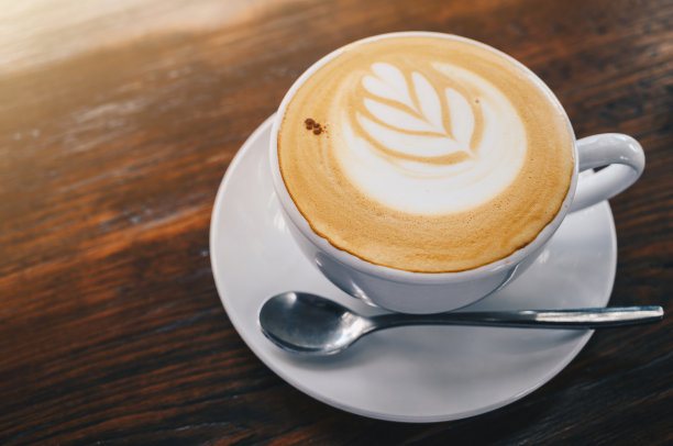 木桌上放着一杯热拿铁咖啡。图片下载