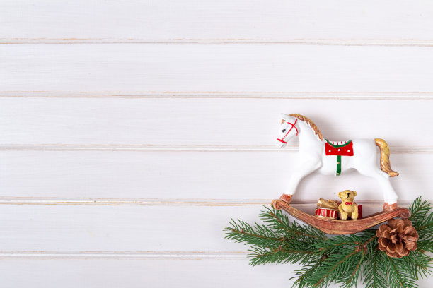 创意复古最小圣诞艺术构图。圣诞复古玩具马，冷杉树枝和松果在白色木制背景。平的。副本的空间。图片下载