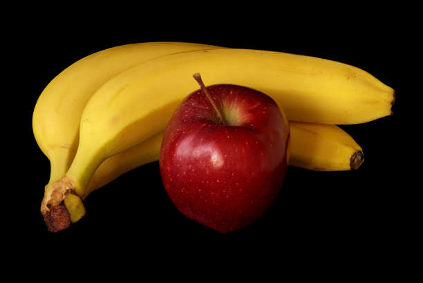 香蕉和苹果放在黑色背景上图片下载