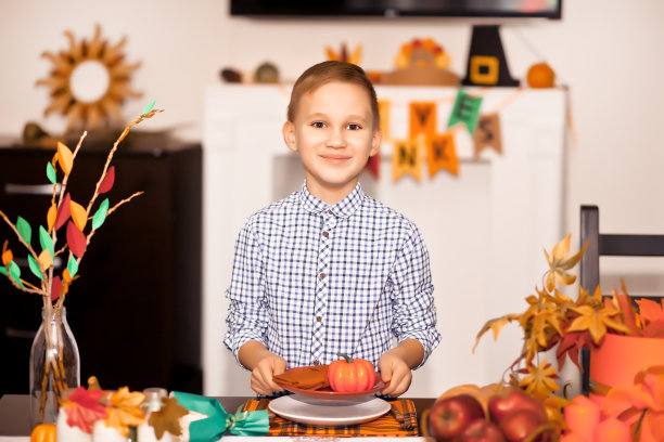 为庆祝感恩节，男孩端上餐桌，装饰客厅。图片下载