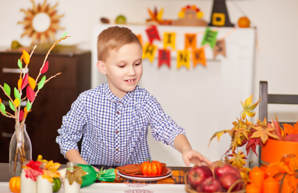 为庆祝感恩节，男孩端上餐桌，装饰客厅。图片下载