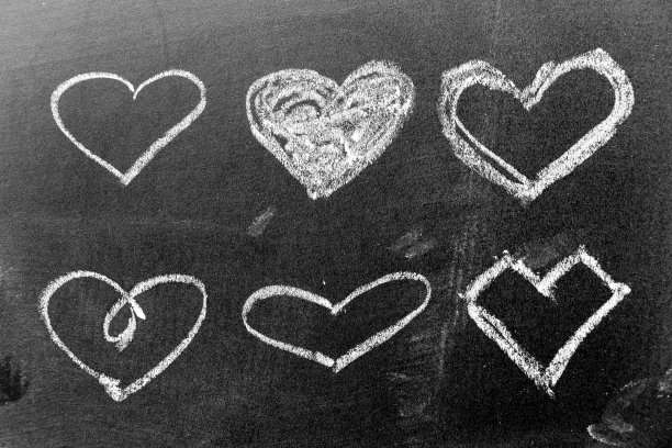 白色粉笔手画在一套心形的黑色板背景图片下载
