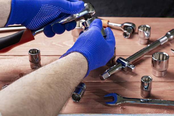 一个带着防护手套的工头用扳手、汽车或摩托车修理概念工作图片下载