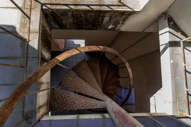 螺旋楼梯模式的上行视图。螺旋楼梯在古老的庭院建筑中盘旋。图片下载