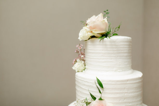 两层白色蛋糕与新鲜玫瑰装饰在中性米色背景复制空间。图片下载