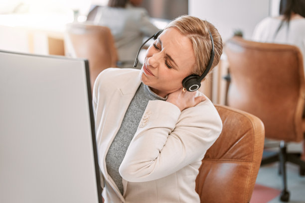 一个迷人的成熟女性呼叫中心代理遭受脖子疼痛，而工作在她的电脑在办公室图片下载
