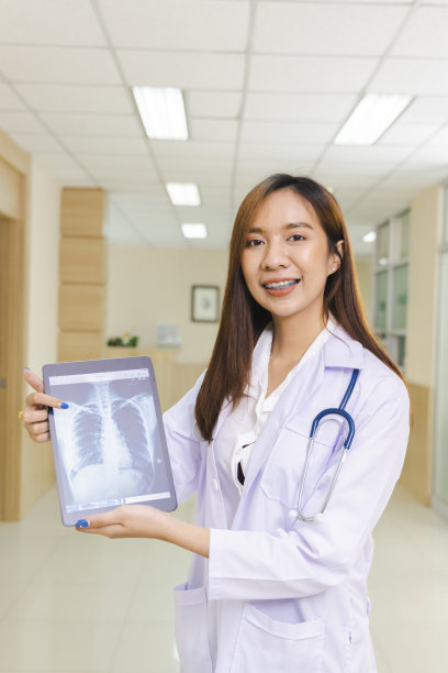聪明的女医生手持平板显示x光照片，站在医院前台。图片下载