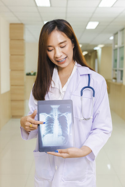 聪明的女医生手持平板显示x光照片，站在医院前台。图片下载