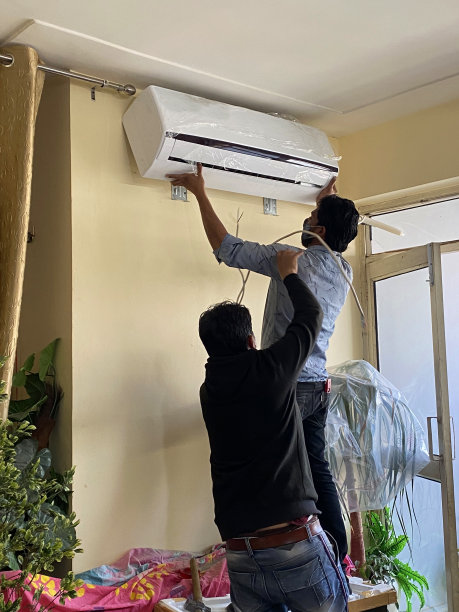 印度勤杂工在公寓家庭房间里安装空调抽油器图片下载