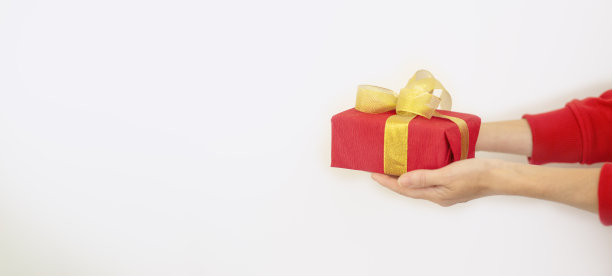 一个穿红毛衣的女人拿着白色背景上的红色圣诞礼物。圣诞节和新年的礼物概念图片下载