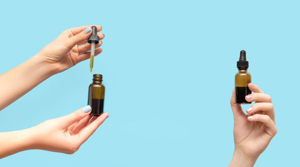 女人的手和蓝色的指甲。女性手持吸管和精油瓶。女性健康保健概念。副本的空间。图片下载