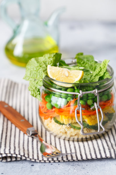 装有新鲜生蔬菜和粗麦粉的玻璃瓶。健康膳食准备-食谱准备照片。玻璃容器中的健康素食菜肴。减肥食物的概念。自制的罐子里的沙拉。图片下载