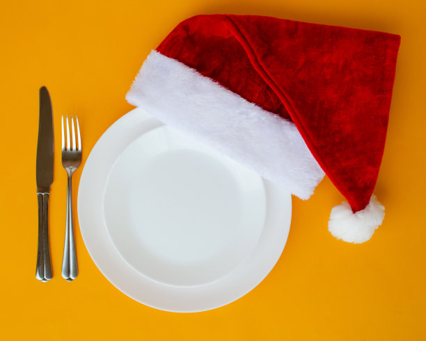 用树枝，盘子，圣诞帽和银器布置的圣诞餐桌。前视图。黄色的圣诞背景图片下载