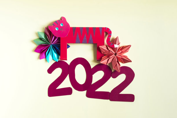 纸色的折纸老虎和彩色的圣诞节装饰在一个明亮的背景。2022年的数字和彩色背景上的纸数字图片下载
