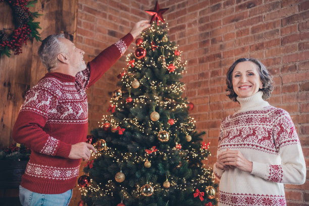照片肖像老人夫妇装饰常青树圣诞树把星星放在顶部图片下载
