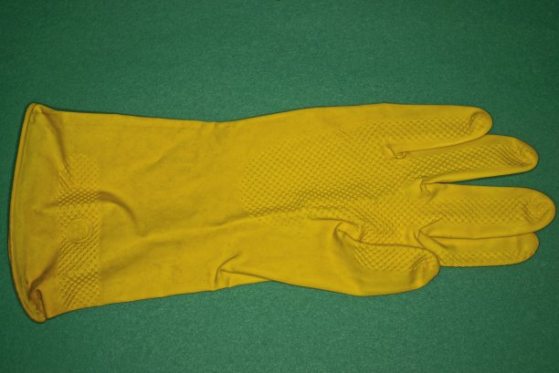 黄色的橡胶手套放在绿色的桌子上图片下载