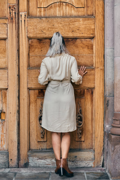 有趣的拉丁年轻女人在木门前摆姿势，年龄在25到35岁之间图片下载