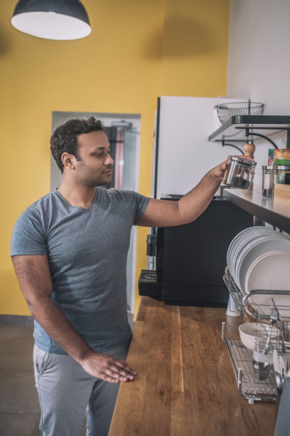 深色皮肤的家伙在办公室厨房选茶图片下载