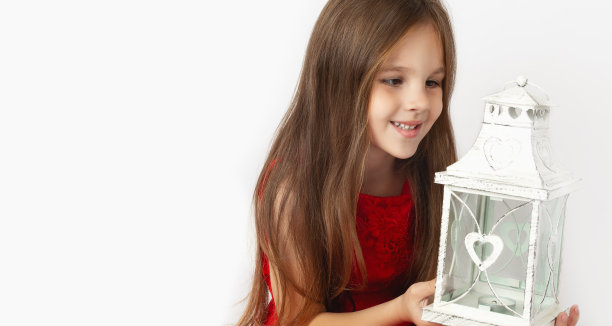 可爱的小女孩穿着优雅的红色连衣裙，挂着白色的圣诞灯笼。生日庆祝，圣诞节，新年。小公主图片下载