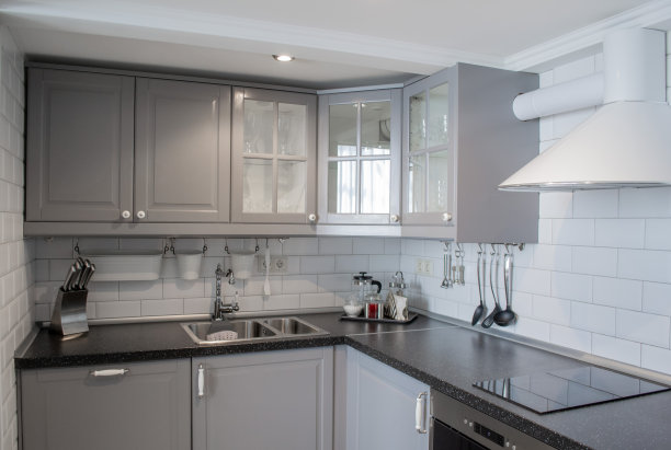 厨房角落采用极简设计，白色和灰色。灰色木质外立面，瓷砖，钢制器皿图片下载