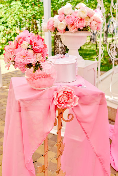 美丽的奶油和粉红色的鲜花在白色的花瓶站在桌上粉红色的布准备的婚礼户外。婚礼花卉装饰。为婚礼准备的漂亮衣服图片下载