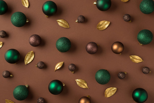在孤立的棕色背景上的绿色棕色金色的圣诞树球和金色的叶子的俯视图照片图片下载