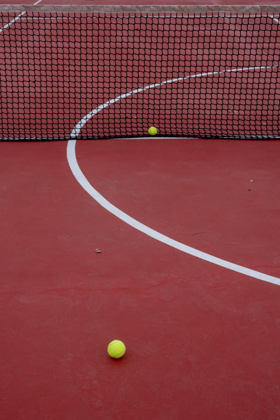 两个球在红色的网球场上图片下载