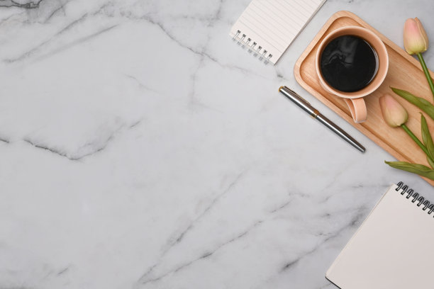 俯视图杯咖啡，记事本和粉红色郁金香在大理石桌上。图片下载