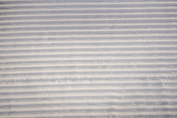 在一个阳光明媚的冬日，完美地修整了空荡荡的滑雪道图片下载