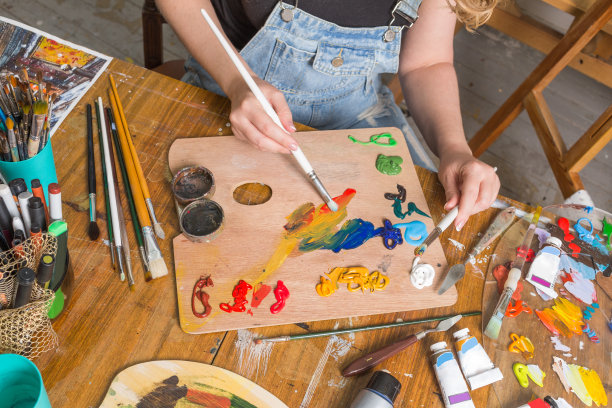 女孩用手绘笔在纸上画画。桌子上的艺术家有不同的绘画用品图片下载